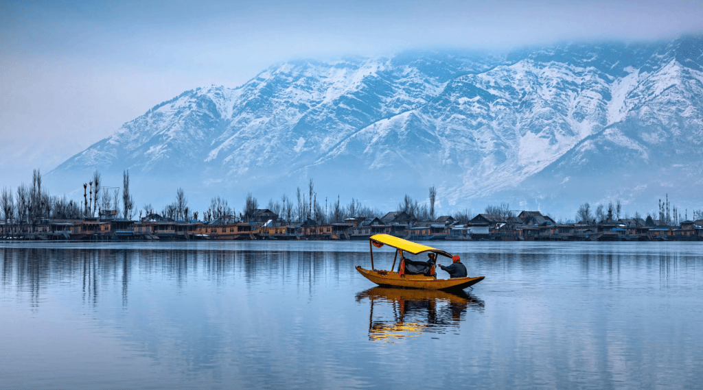 A serene boat gliding on water, framed by majestic mountains in the background.