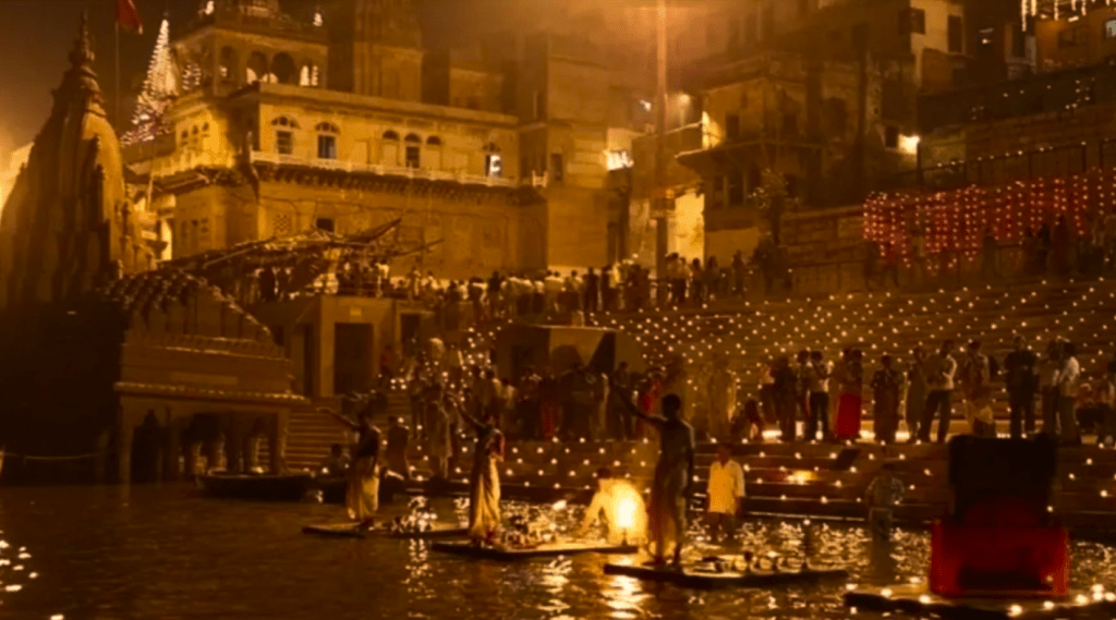 People standing on boats in water, holding candles. A serene scene of unity and remembrance.