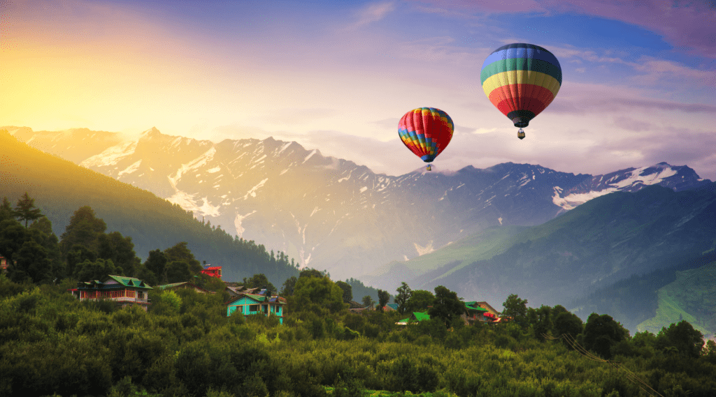 Hot air balloons soar above a picturesque mountain village, creating a colorful spectacle in the sky.