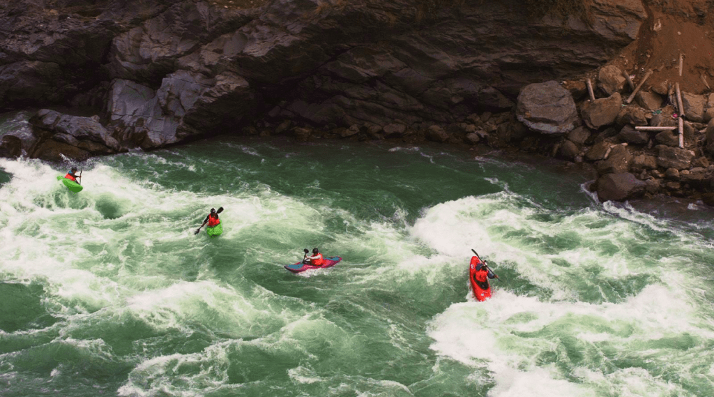 Aerial view of river with three kayaks, adventurously rowing the water stream.
