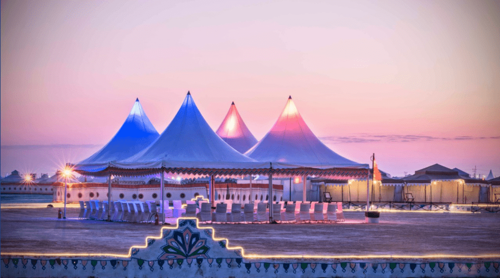 Tents illuminated at dusk in the desert, creating a captivating scene of warm, glowing lights amidst the vast darkness.