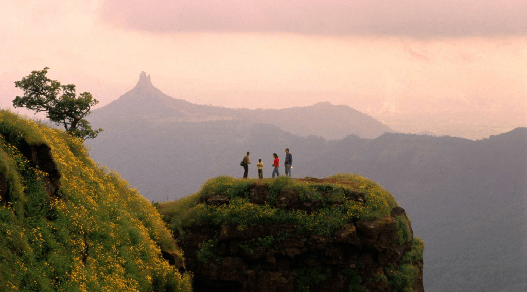 Three people standing on a mountain peak, gazing at the picturesque valley below.