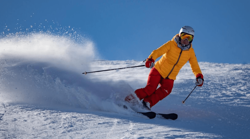 A skier in a yellow jacket gracefully glides down a snowy slope, showcasing their skills and love for winter sports.
