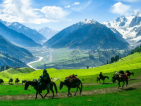 People riding horses through a lush green valley under a clear blue sky.