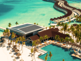 A beach resort featuring a long wooden pier extending into the ocean under a clear blue sky.