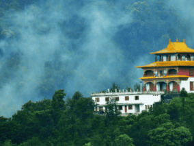 A temple perched on a hill, surrounded by lush green trees, creating a serene and picturesque landscape.