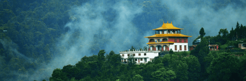 A temple perched on a hill, surrounded by lush green trees, creating a serene and picturesque landscape.