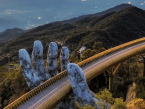 The Golden Bridge in Vietnam, featuring giant stone hands supporting a golden walkway amidst lush green mountains.
