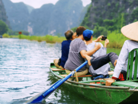 Three people sit in a small boat, enjoying a peaceful moment on the calm water under a clear sky.