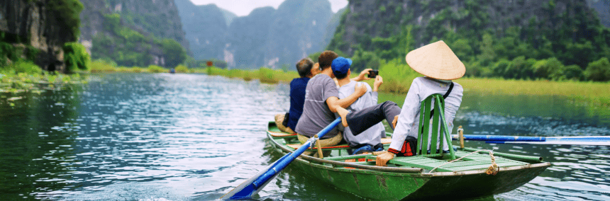 Three people sit in a small boat, enjoying a peaceful moment on the calm water under a clear sky.