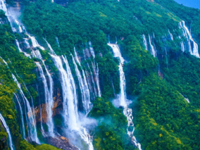 A cascading waterfall flows down a rocky mountain, surrounded by lush greenery and steep cliffs.