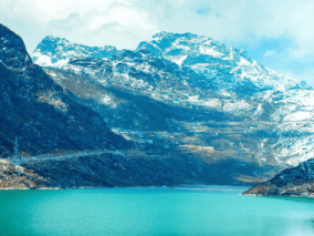A serene lake nestled among majestic mountains, with a blanket of snow covering the peaks.