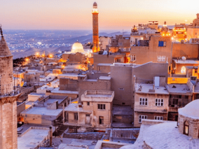 The old city at sunset, showcasing a blend of warm colours in the sky and the silhouette of buildings against the horizon.