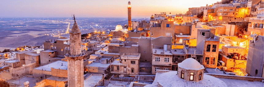 The old city at sunset, showcasing a blend of warm colours in the sky and the silhouette of buildings against the horizon.
