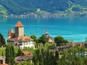 A scenic view of a Switzerland lake featuring a grand castle above it, with natural beauty enhancing the enchanting landscape.